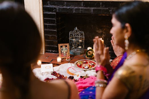 Two women engaged in prayer at a Hindu altar, adorned with candles and traditional offerings, showcasing spirituality and culture.