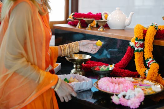 A woman in traditional attire participates in a colorful Indian cultural ceremony with flower garlands and offerings.